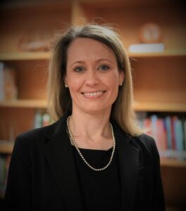 A half-body photo of a blonde-haired woman smiling.